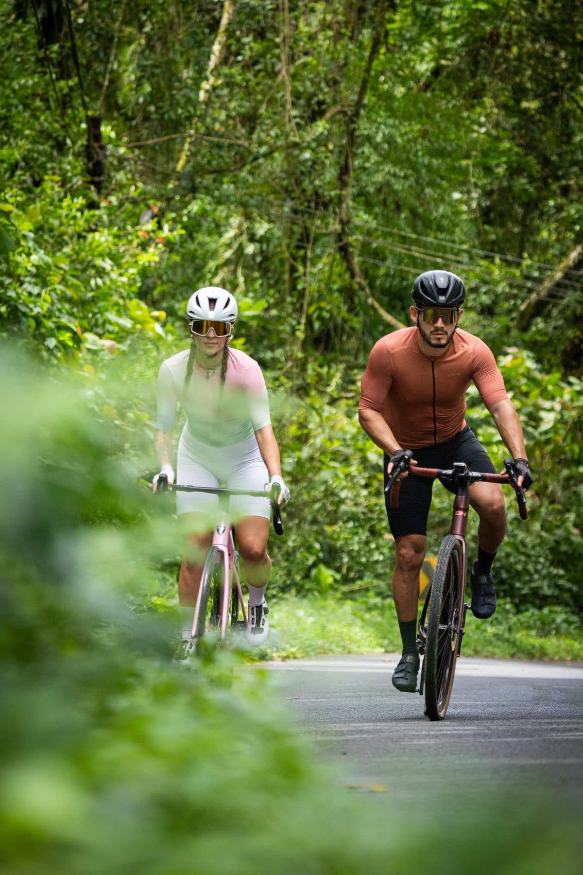 Dos ciclistas rodando en carretera rodeados de bosque en La Fortuna