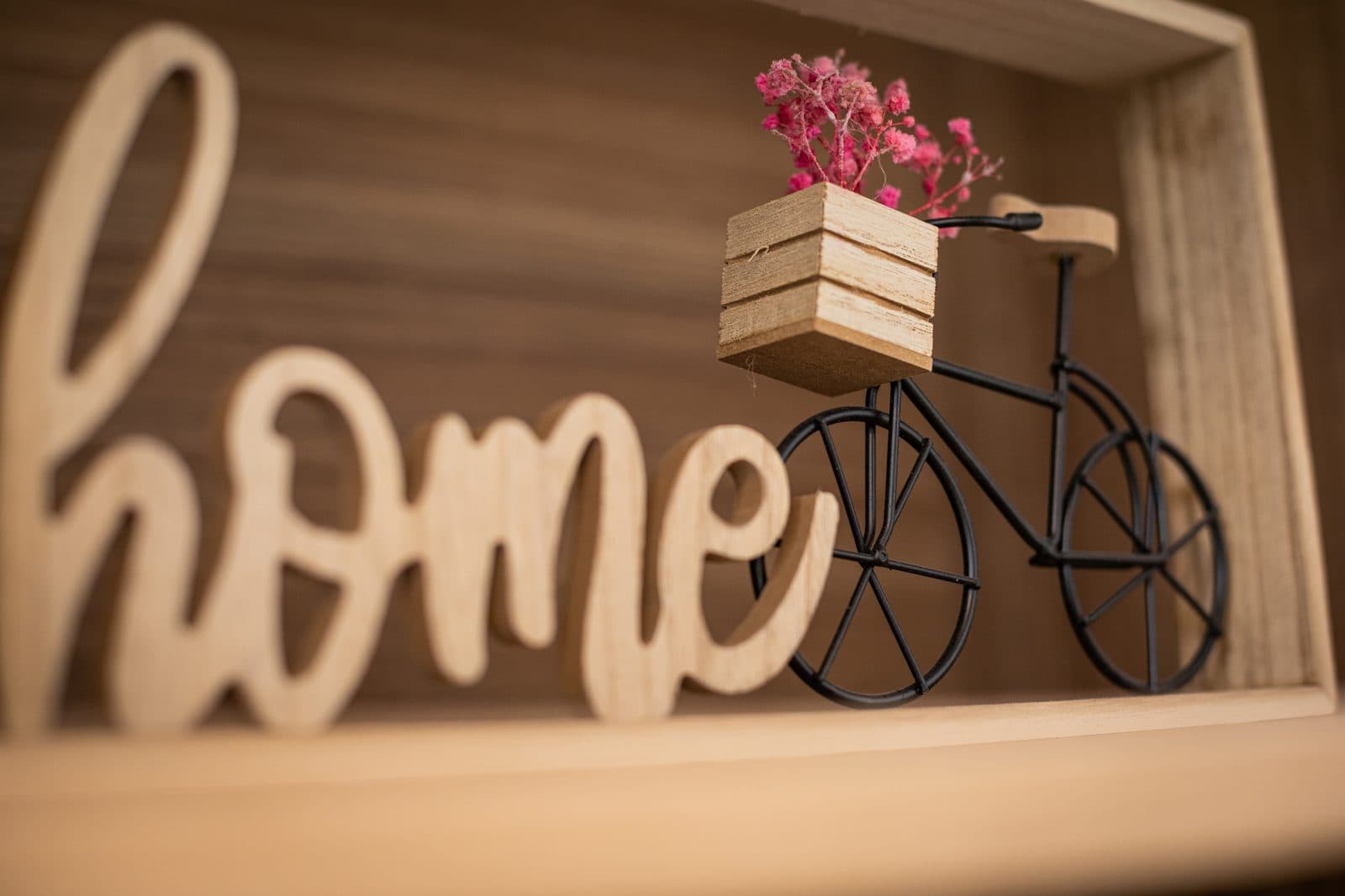 Detalle de una villa de Bike & Bed: un letrero de madera que dice «home» junto a una bicicleta decorativa